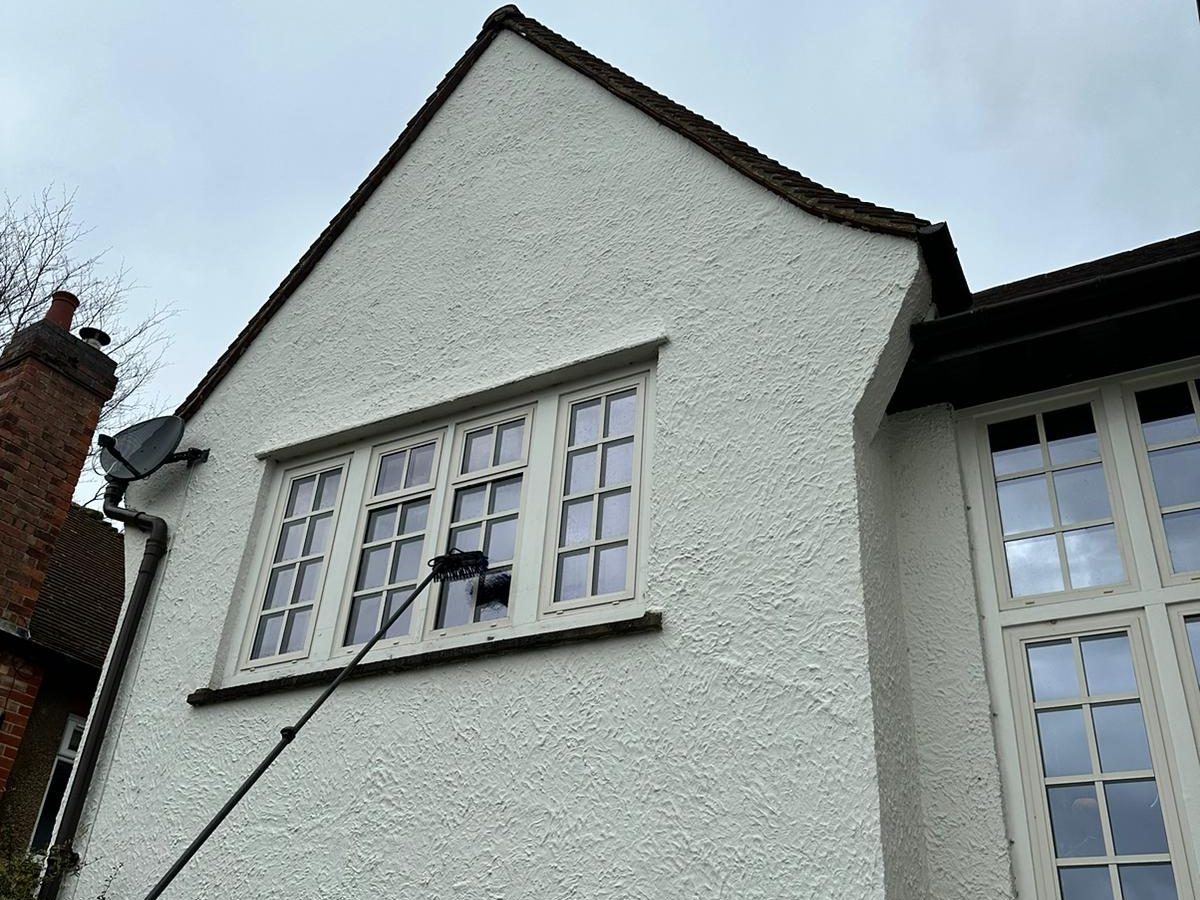 House with pitched roof, pole brush cleaning the top large window